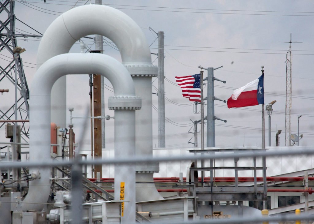 FILE PHOTO: FILE PHOTO: A maze of crude oil pipe and equipment is seen with the American and Texas flags flying during a t...