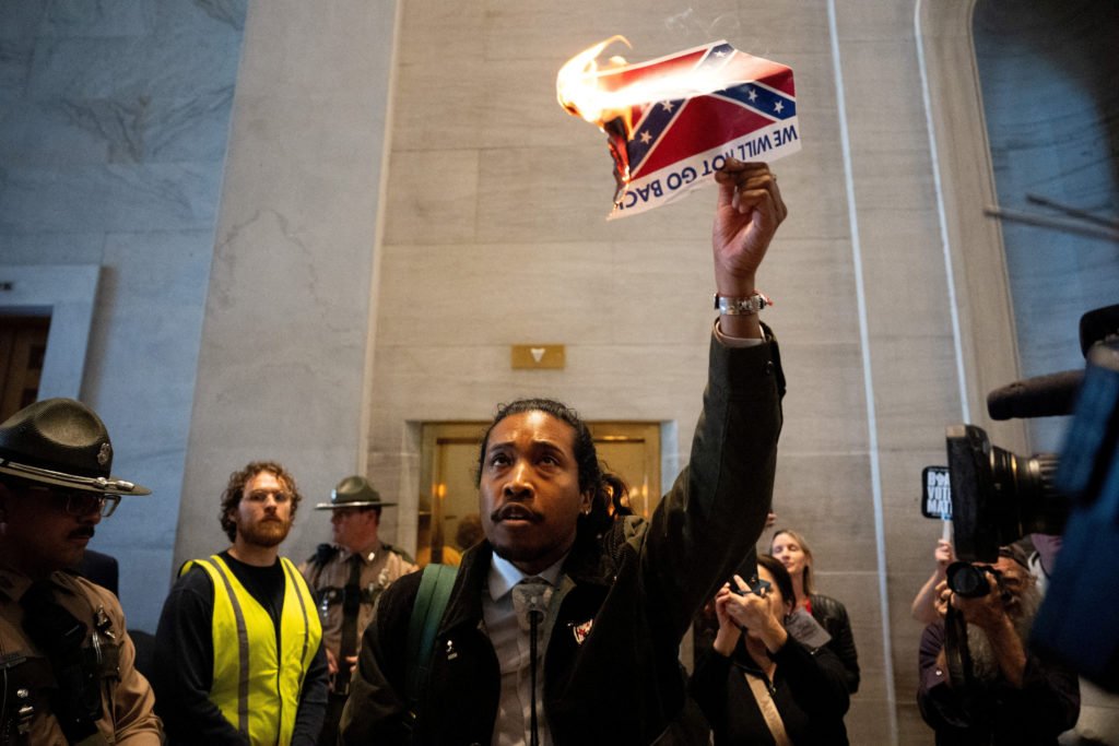 Democratic state representative Justin Jones walks out of the House Chamber and burns a photo of the Confederate Flag